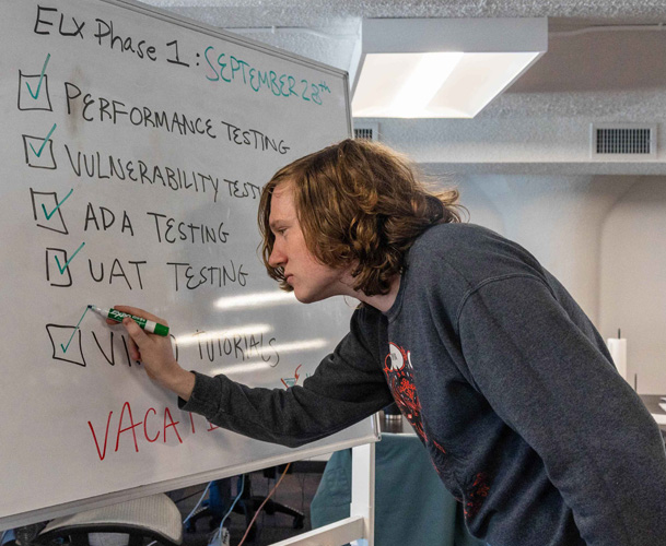 picture of jd a software engineer checking items on a whiteboard with a green marker